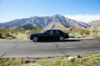 Rolls Royce travelling on country road with mountains in background