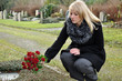 Frau legt Blumen auf Grab