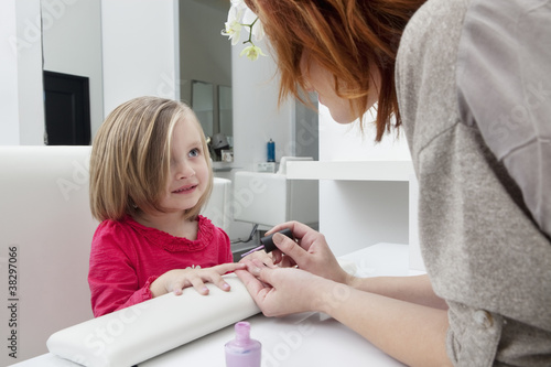 Photo: Woman applying nail polish on little girl's hand Woman applying nail polish on little girl's hand