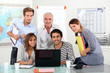 Young team of people sitting around a laptop with an older guy