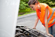 Young driver bent over the car engine