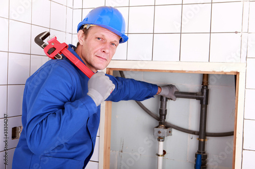 Photo: Experienced plumber using a large wrench in a bathroom Experienced plumber using a large wrench in a bathroom
