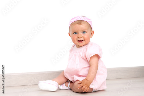 Photo: Baby girl with blue eyes sitting on the floor Baby girl with blue eyes sitting on the floor