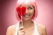Young pink blondie with valentine lollipop on a pink background