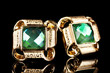 beautiful gold earrings with emerald on black background