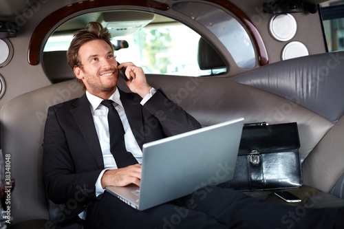 Photo: Smiling businessman in luxury car working Smiling businessman in luxury car working