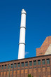 Foto: White smokestack and red brick building White smokestack and red brick building