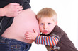 kleiner bruder horcht am babybauch der mutter