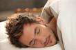 Handsome young man asleep in bed