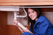 Young woman fitting the waste pipe on a kitchen sink