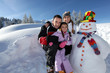 Photo: couple posing with child beside snowman at mountain resort couple posing with child beside snowman at mountain resort
