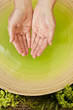 Woman's Hands in Green Liquid at Health Spa