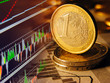 Euro coin and stock graph on a screen.