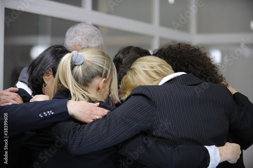 Photo: Team building event: businessmen in 'group hug' in office Team building event: businessmen in 'group hug' in office