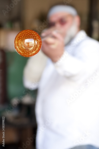 Photo: Glass blower shaping molten glass into a drinking goblet Glass blower shaping molten glass into a drinking goblet