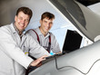 Motor mechanics checking the engine bay with diagnostic computer