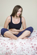 Schöne Frau mit Bauchschmerzen im Bett sitzend