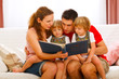 Mother and father looking photo album with twins daughters