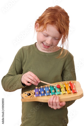 Foto: Junges rothaariges Mädchen musiziert auf einem Spielzeugxylophon Junges rothaariges Mädchen musiziert auf einem Spielzeugxylophon
