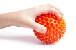 Boy hand with Spiny plastic orange massage ball on white