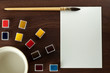 Vintage watercolor paint set with blank paper, water and brush.