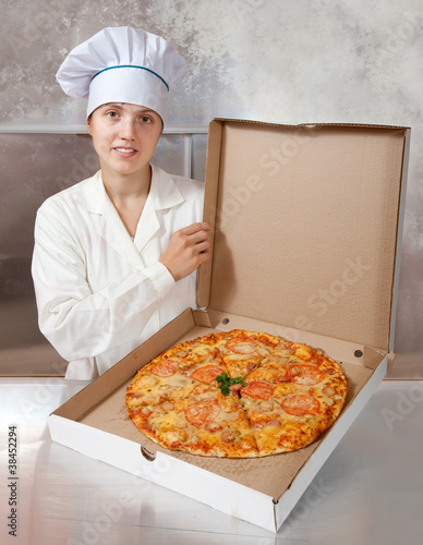 Photo: female cook with cooked pizza female cook with cooked pizza