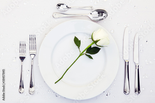 Photo: Table place setting with white rose on the plate Table place setting with white rose on the plate