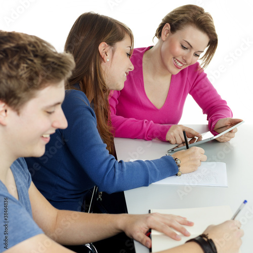 Photo: Young students learning together with touchpad and books Young students learning together with touchpad and books