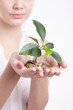 woman's hands holding plant sprouting from a handful of coins