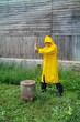 An elderly man in a yellow raincoat with an ax