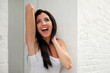 happy brunette female beside white brick wall