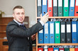 Handsome male business executive standing behind a bookstand