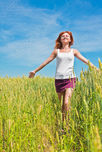 Photo: Beautiful young woman running through a wheat field Beautiful young woman running through a wheat field