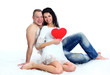 Couple sitting on the floor with a big red heart Couple sitting on the floor with a big red heart