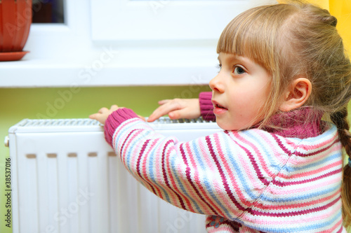 Photo: Girl warm one's hands near radiator Girl warm one's hands near radiator