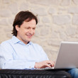 lächelnder mann mit laptop zu hause
