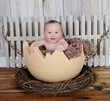 happy baby sitting in giant egg prop