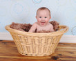 sweet baby sitting with big smile in wicker basket