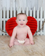 sweet baby boy sitting with large red heart