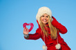 woman in red coat holding heart shape