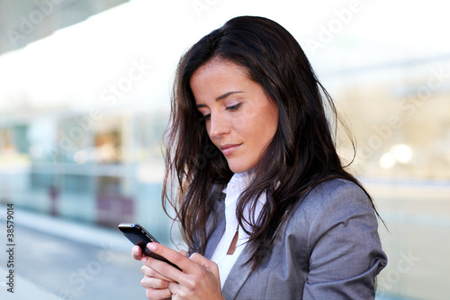 Photo: Businesswoman sending message with smartphone Businesswoman sending message with smartphone