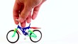 Hand does tricks on toy bike, jump and rotate it