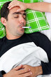 Photo: Sick hispanic man laying in bed with a thermometer Sick hispanic man laying in bed with a thermometer
