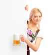 Photo: German girl holding a pint of beer behind a blank billboard German girl holding a pint of beer behind a blank billboard