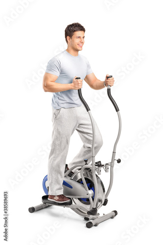 Foto: Handsome man exercising on a cross trainer machine Handsome man exercising on a cross trainer machine