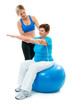 Senior woman doing fitness exercise with help of trainer in gym