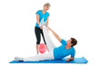 Senior woman doing fitness exercise with help of trainer in gym