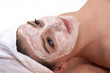 junge frau mit gesichtsmaske beim wellness