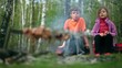 Boy and girl sit and talk, meat cooking on embers