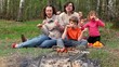 Family sit on grass cover by plaid and eats kebab on skewers Family sit on grass cover by plaid and eats kebab on skewers